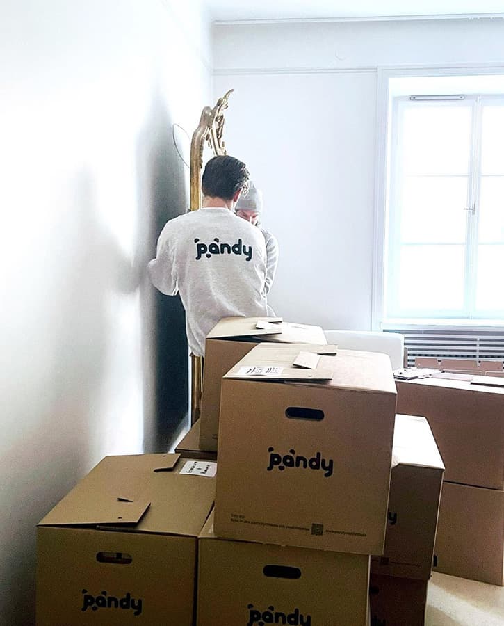Pandys flyttkillar lyfter en stor och tung spegel från väggen
