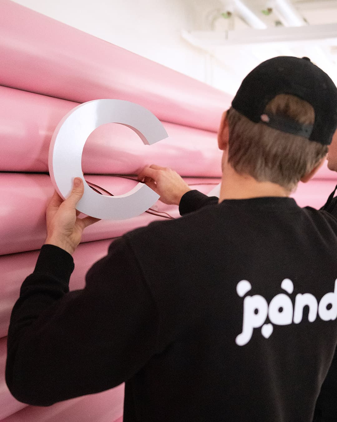 Pandy-fixare monterar en stor bokstav på en rosa vägg