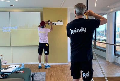 Två Pandy-fixare sätter upp en skylt på ett företags kontor